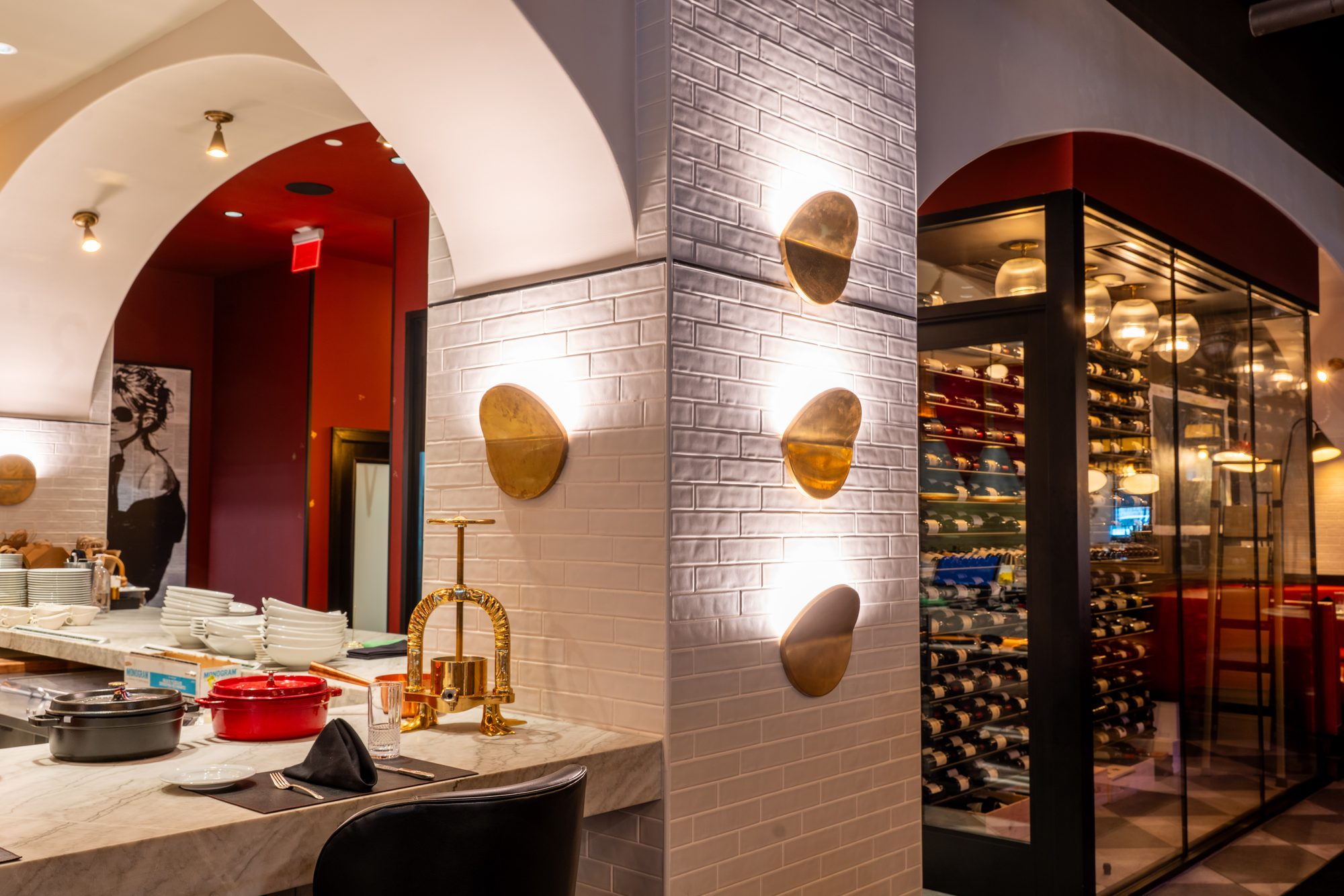 Arched white-brick dining room with brass sconces and wine wall at Francois, Austin