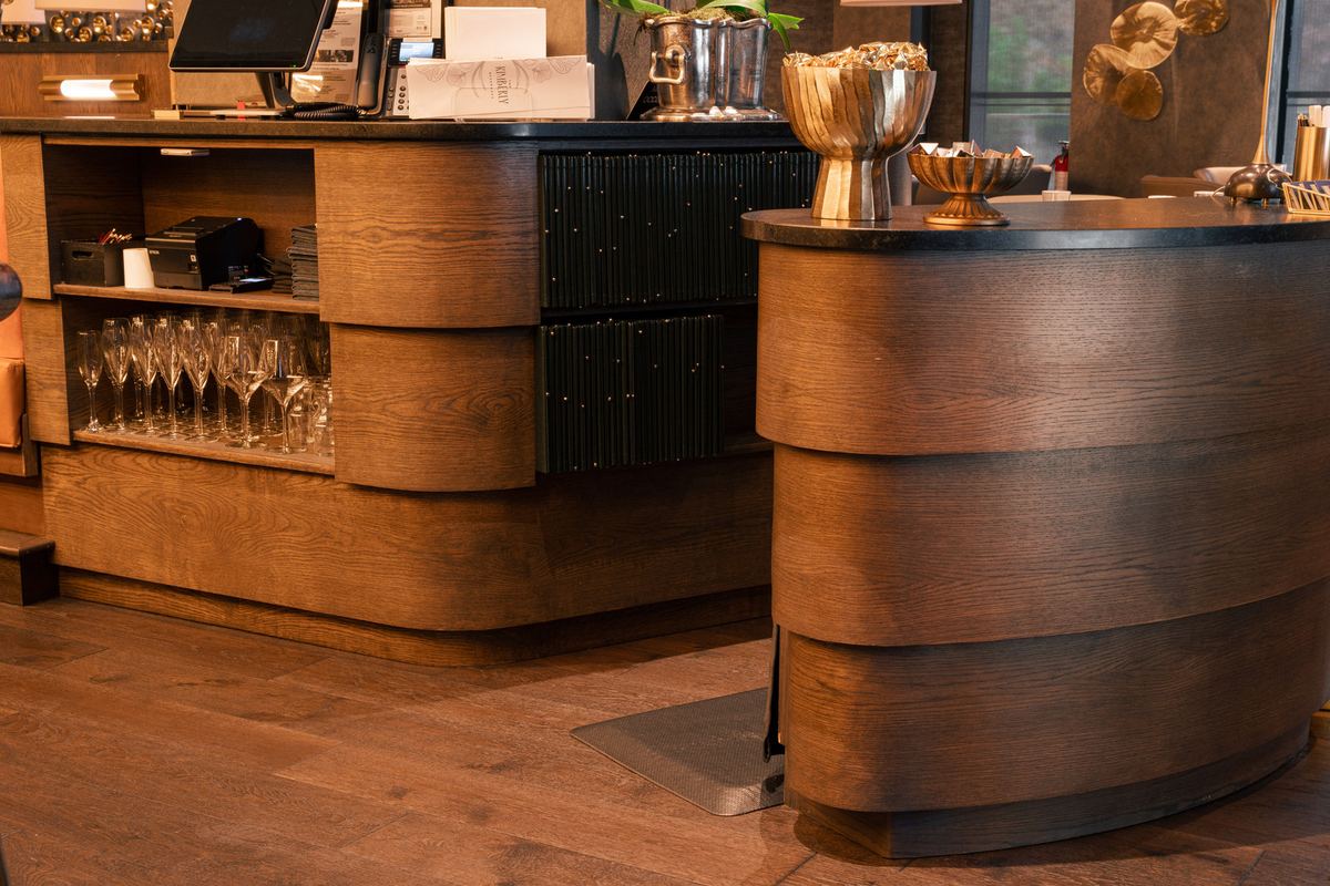Curved wood-clad host stands with brass tops