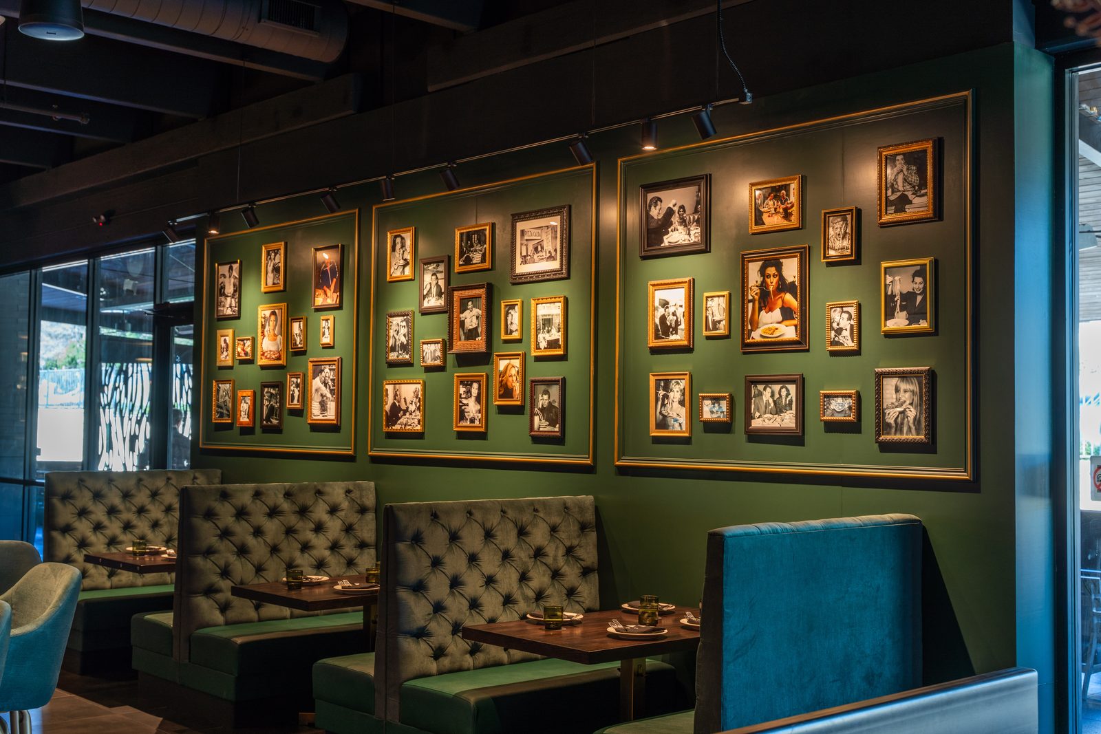 Green tufted booths under a gallery wall of framed photos