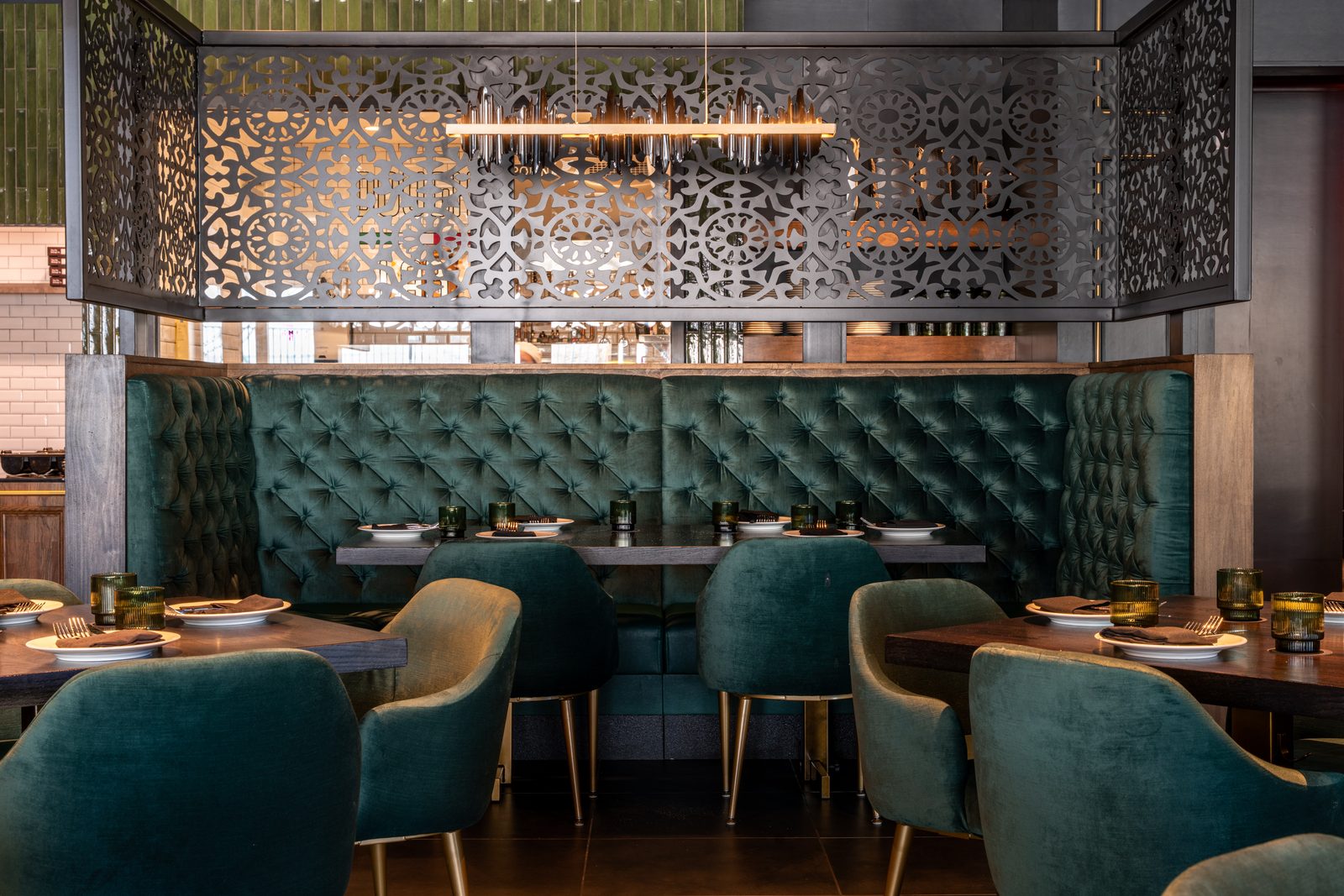 Laser-cut decorative steel screen behind tufted booth seating